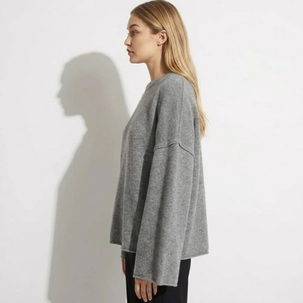 Side profile view of the relaxed fit and wide bell sleeves on the grey cashmere crewneck sweater by Kouvr Fashion.