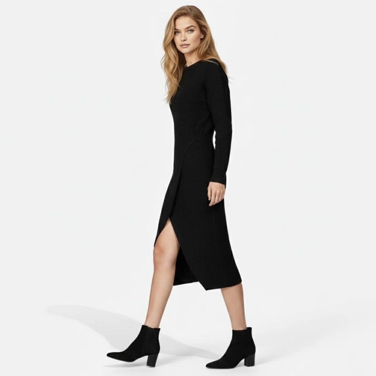 Side profile of a model walking in the Kouvr Fashion Janessa black long sleeve sweater dress, highlighting the asymmetrical hem and high slit.
