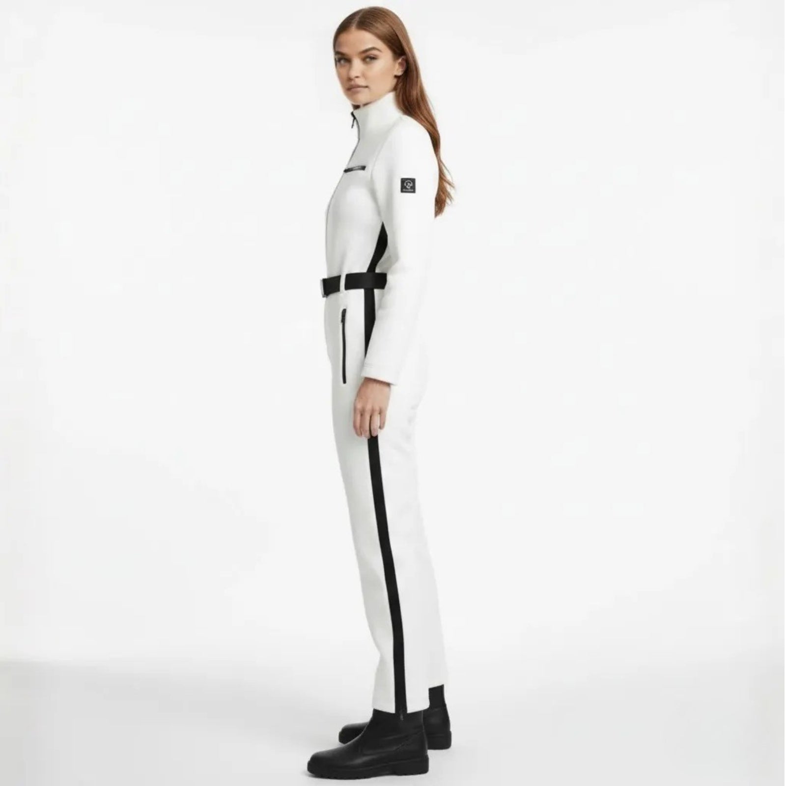 Side view of a model in the Kouvr Fashion Junnie white ski suit showing the black side stripe and brand logo on the arm.