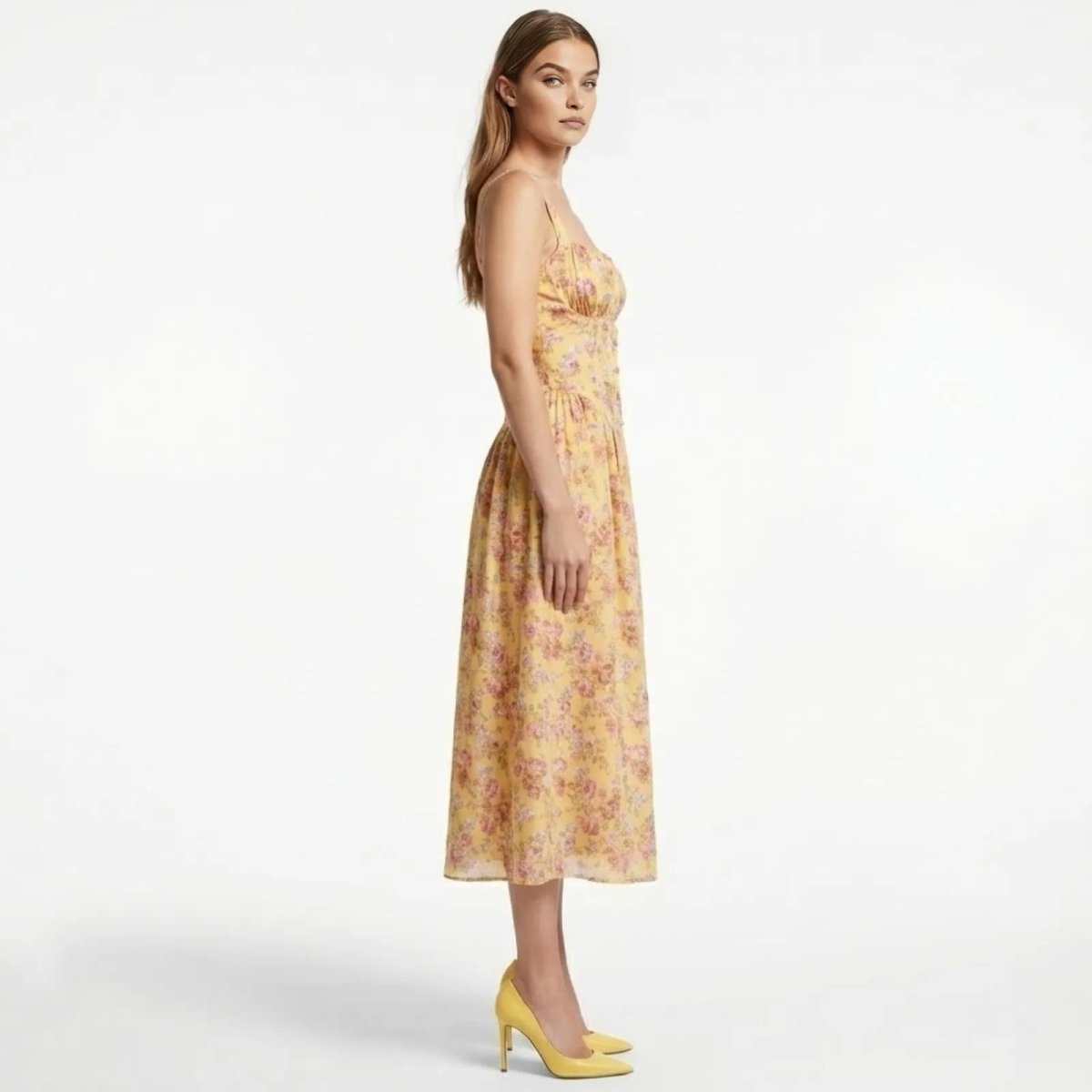 Side profile of a model in a yellow floral A-line midi dress by Kouvr Fashion, showcasing the fitted waist and flowing skirt.
