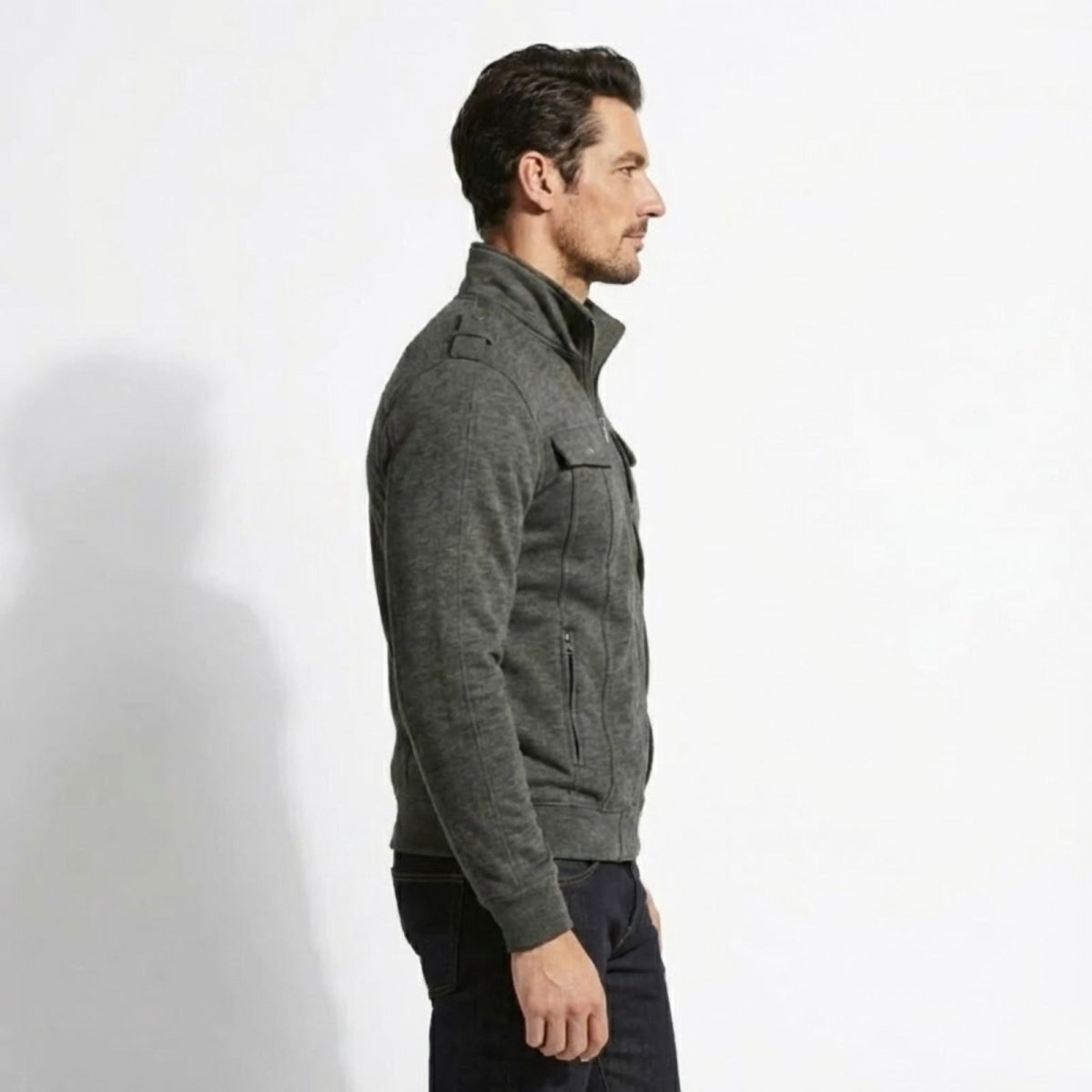 Side profile of a model wearing the slim fit Kouvr Fashion Kent military jacket in dark grey showing the stand collar detail.