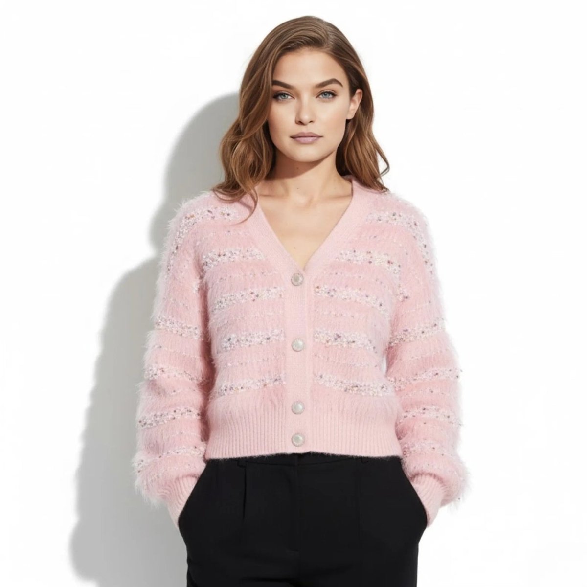 Model wearing the Kouvr Fashion Kyra pink sequin fuzzy cardigan with black trousers, facing forward.