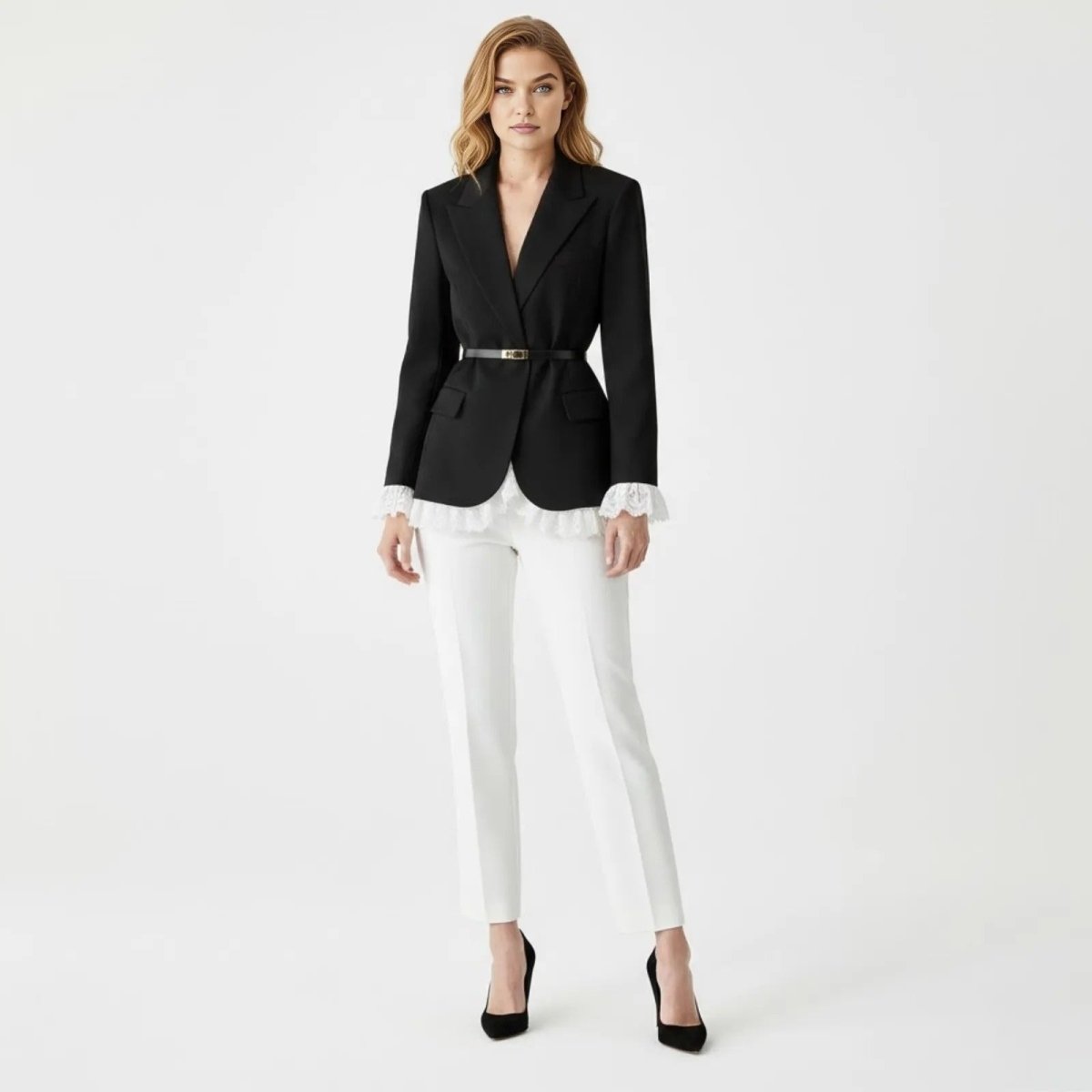 Model wearing the Kouvr Fashion black tailored blazer with a skinny belt, showing the white lace trim at the hem and cuffs, paired with white trousers.