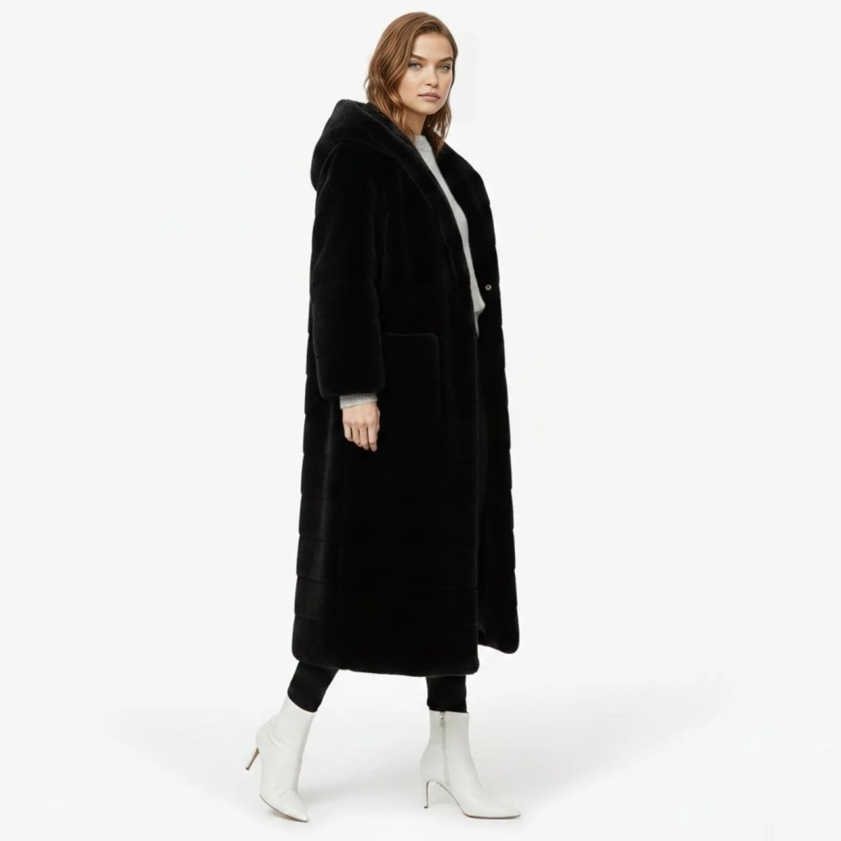 Side profile of a model wearing a full-length black hooded faux fur coat, showcasing its length and silhouette.