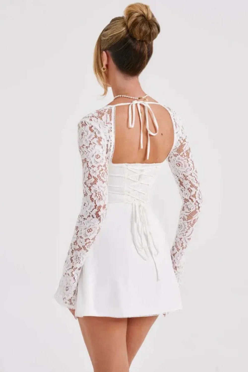 Model from behind wearing the Kouvr Fashion Louise white lace corset mini dress showing the adjustable back lacing
