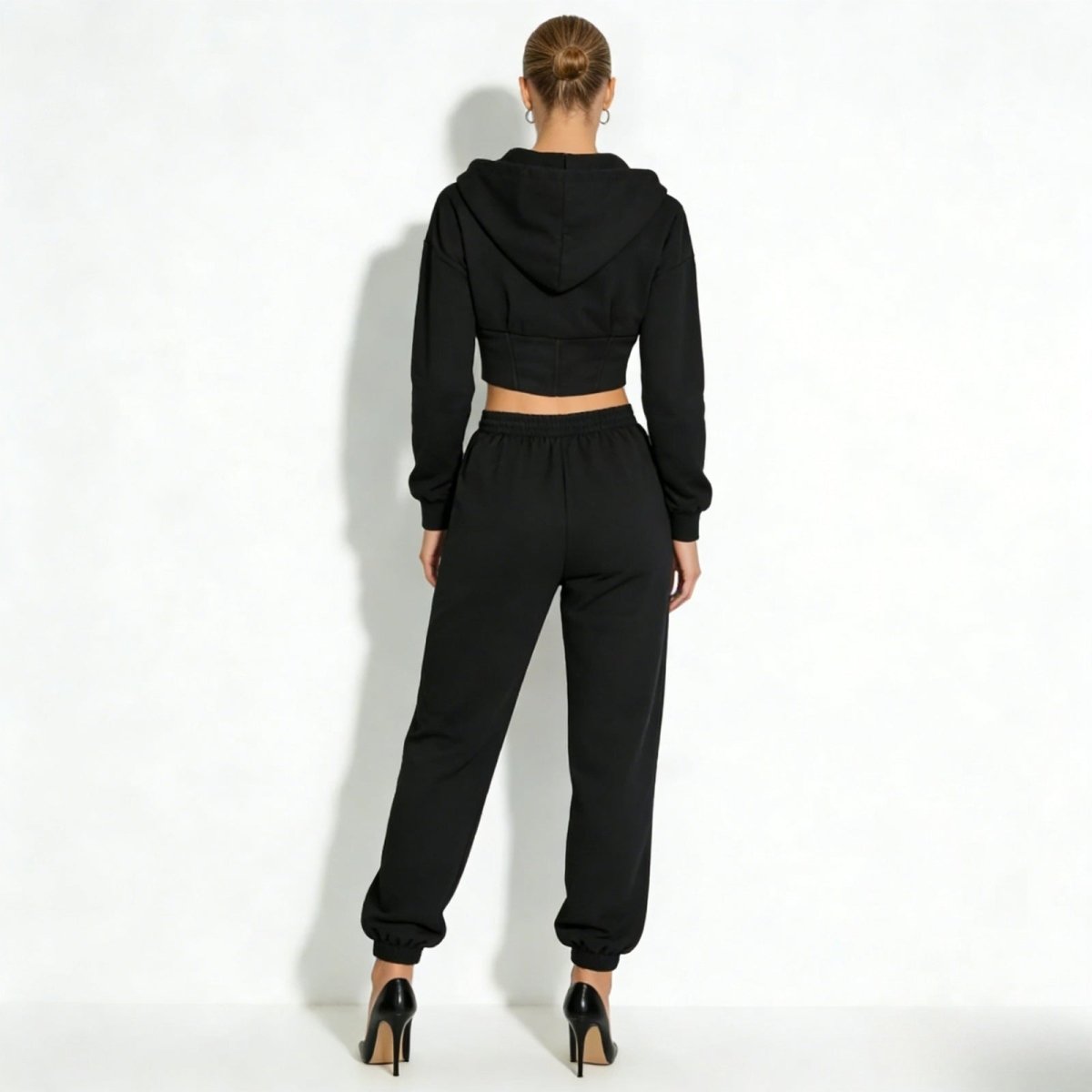 Rear view of a model wearing the black two-piece loungewear set from Kouvr Fashion, highlighting the corseted waist detail.