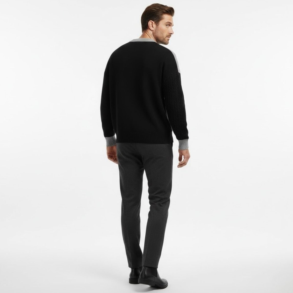 Rear view of a male model wearing the Kouvr Fashion black sweater with grey cable knit sleeve detail.
