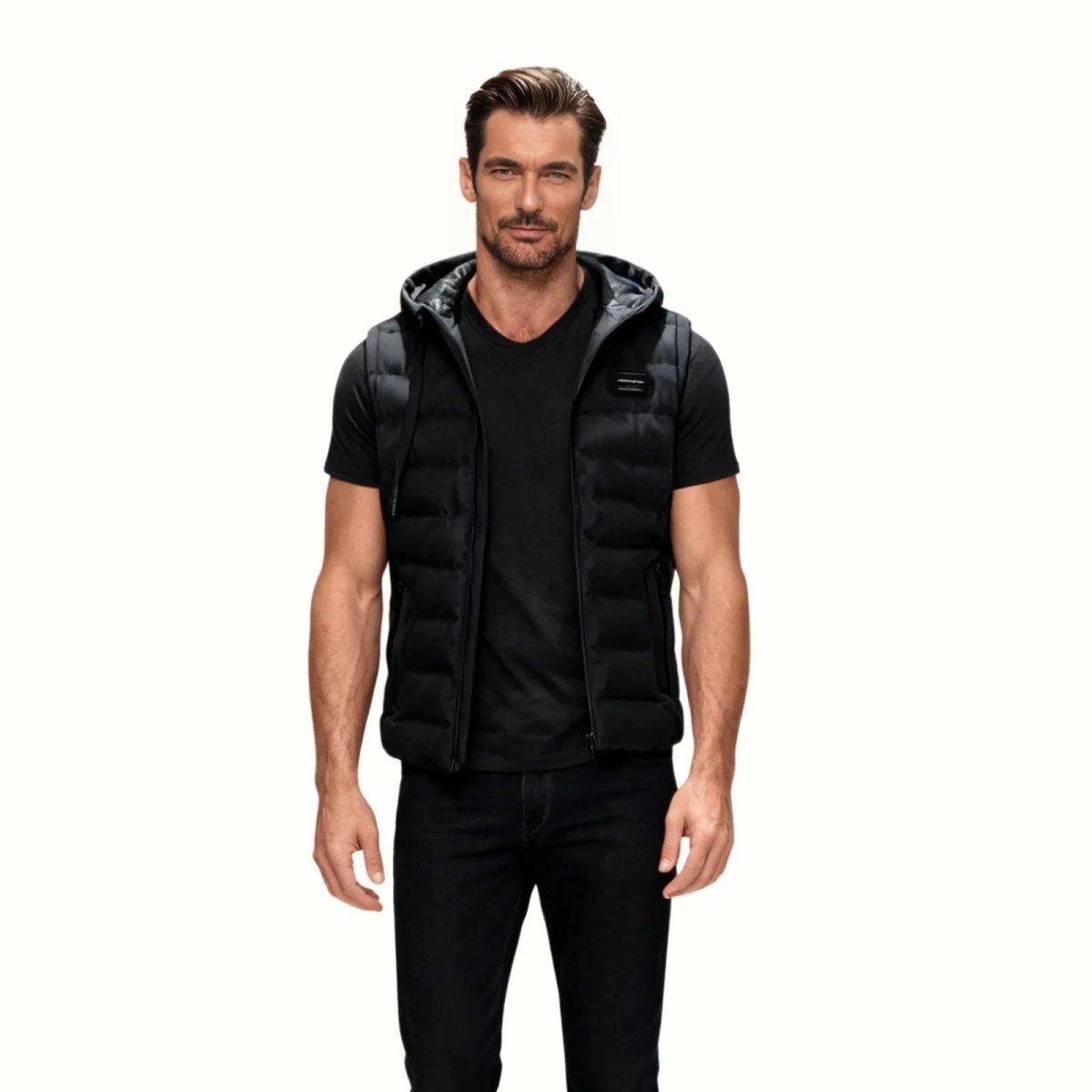 Male model wearing the Kouvr Fashion black hooded puffer vest from the front over a black t-shirt and black jeans. 
