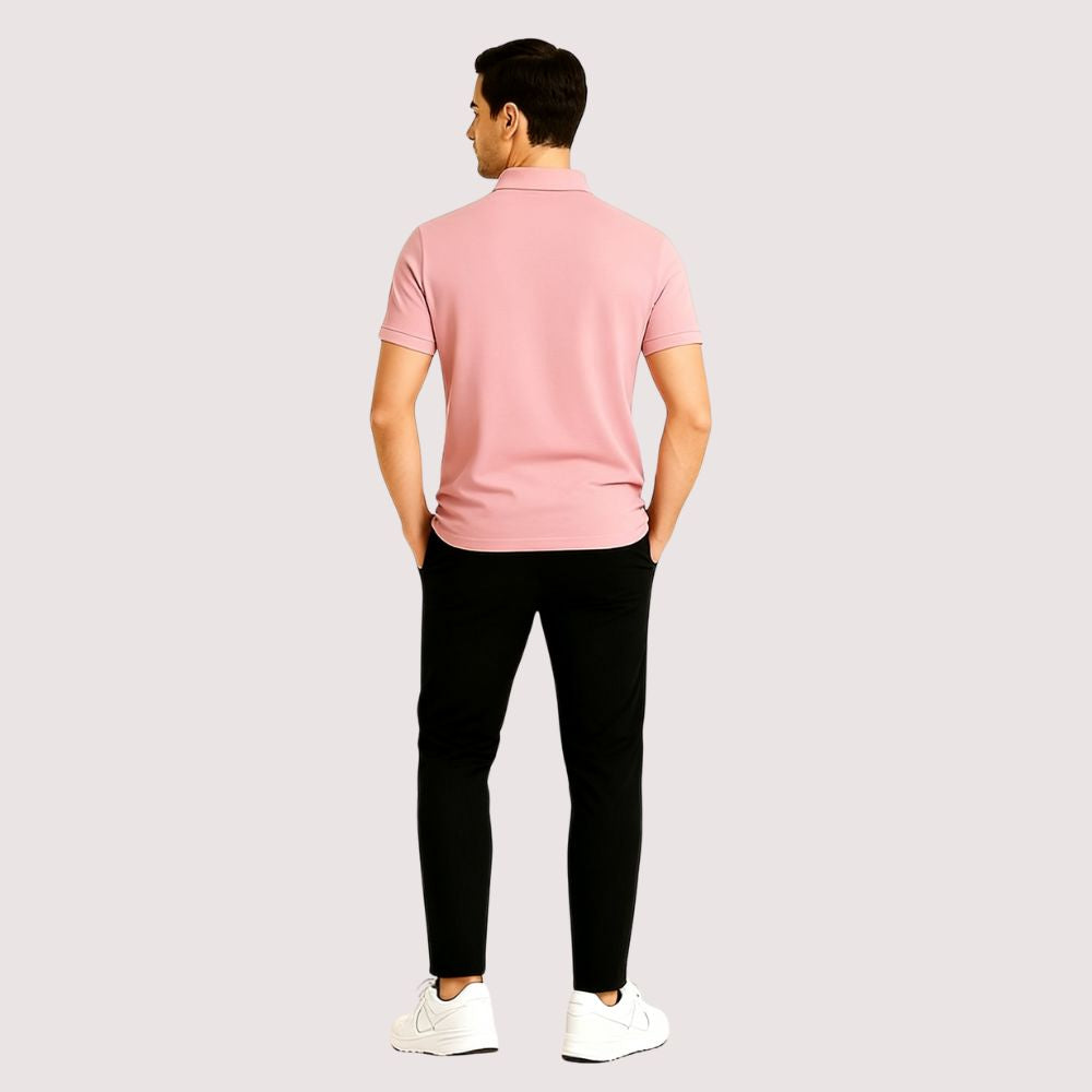 Man wearing the Kouvr slim fit Rose Quartz pink polo shirt with black trousers against a white background.