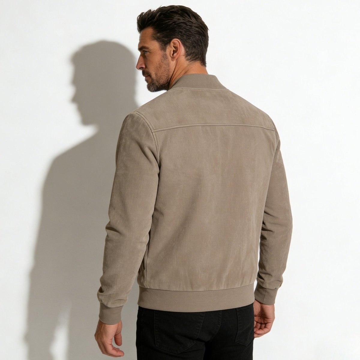 Back view of the Kouvr Fashion suede bomber jacket worn by a model, highlighting the unique vertical ribbed suede panel on the back. 