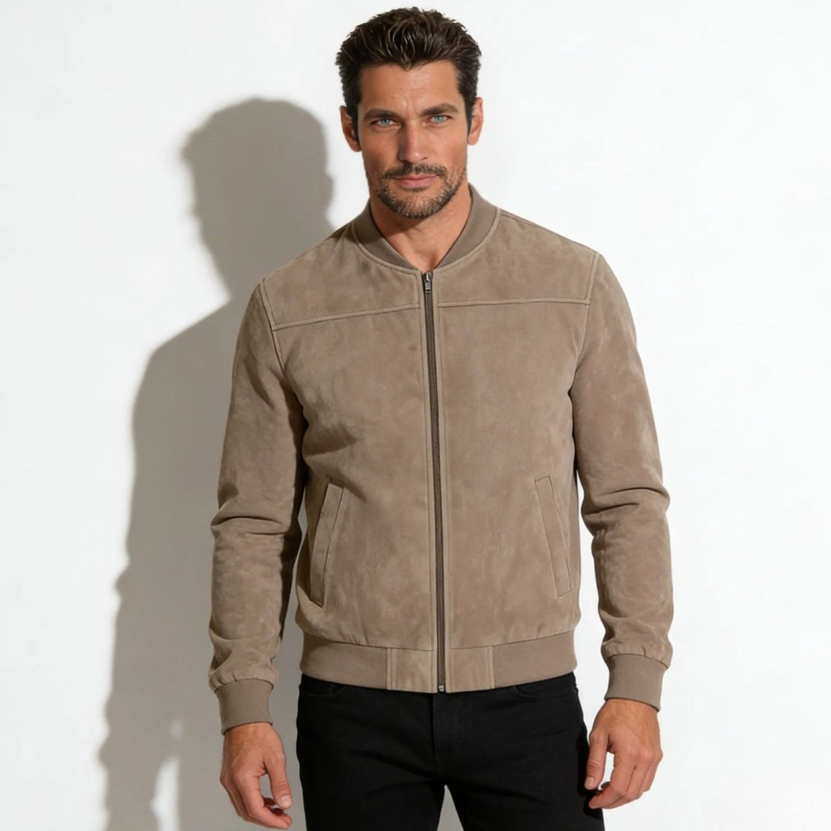 A man with dark hair and blue eyes wearing the Kouvr Fashion Michael Khaki Suede Bomber Jacket with black jeans against a white background.