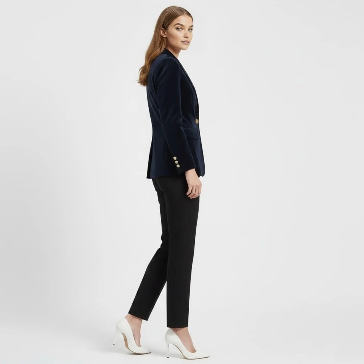 Side profile of a woman in a tailored navy blue velvet blazer by Kouvr Fashion, showcasing the fit and gold button cuff details.