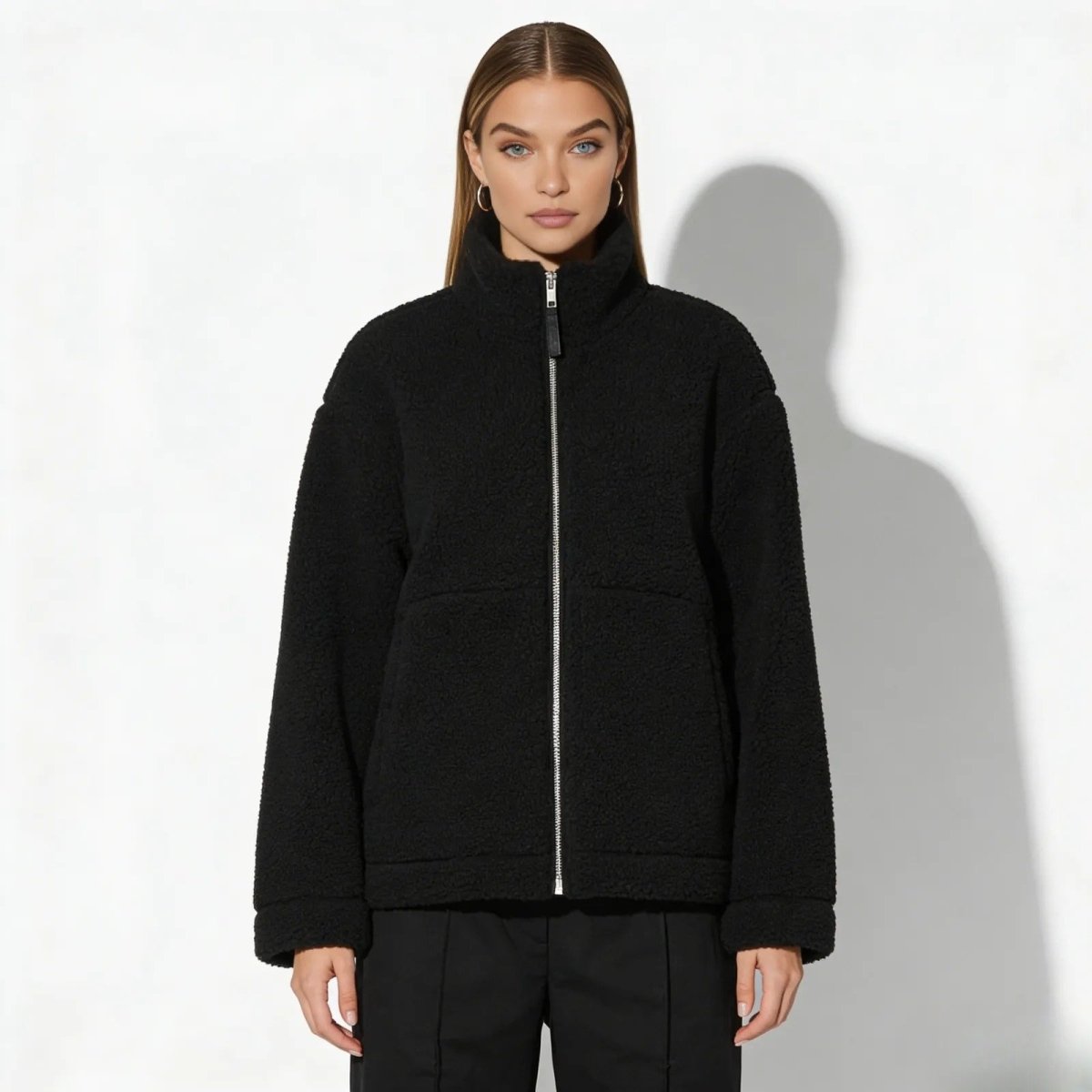 Model wearing the Kouvr oversized black sherpa fleece jacket with a high neck, showcasing its relaxed fit from the front against a white background.