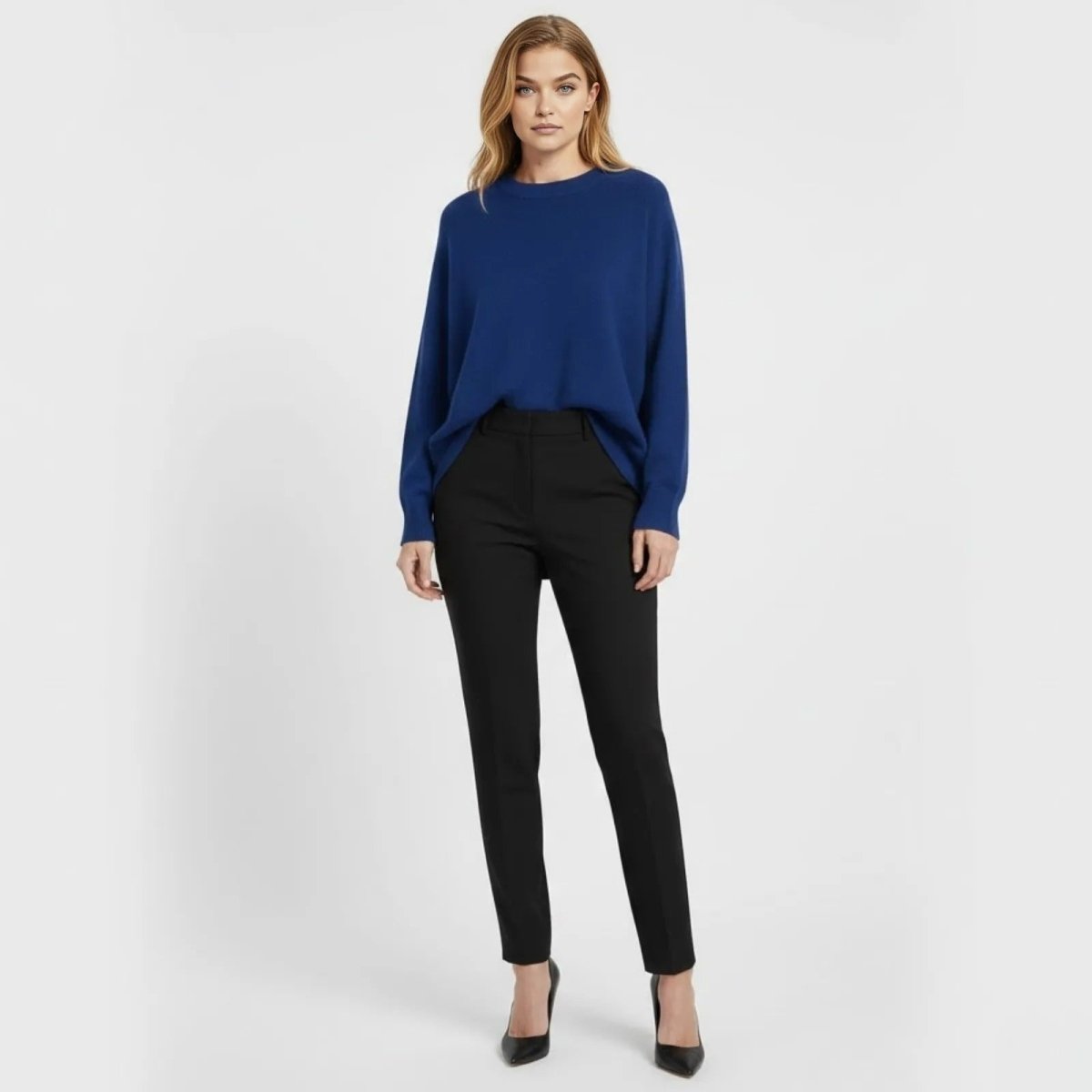 Model facing forward wearing the Kouvr Fashion oversized crewneck sweater in cobalt blue, styled with slim-fit black trousers and black heels against a white background.