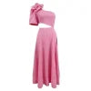 Model wearing Kouvr's pink one-shoulder midi dress with a large rose on the shoulder and a side waist cutout, standing by a pool at night