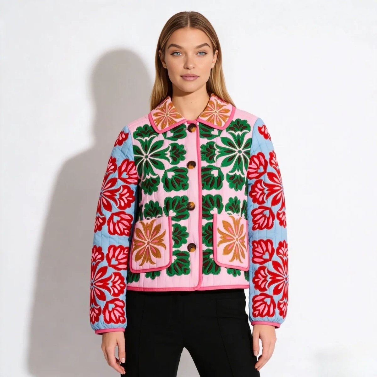 Model wearing the Kouvr Fashion pink and green quilted jacket with intricate red and green floral embroidery, featuring a collar and patch pockets.