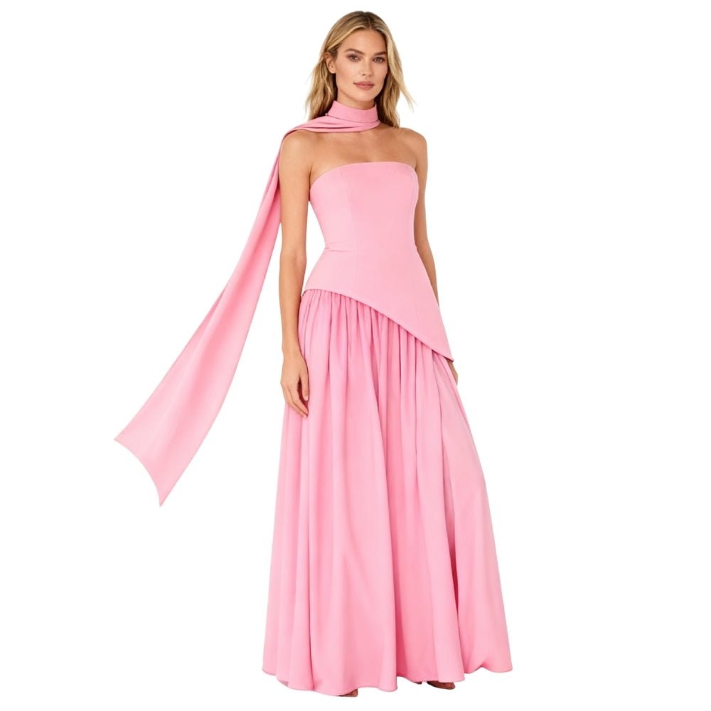 Woman wearing a pink Kouvr strapless gown with a flowing fabric on a white background