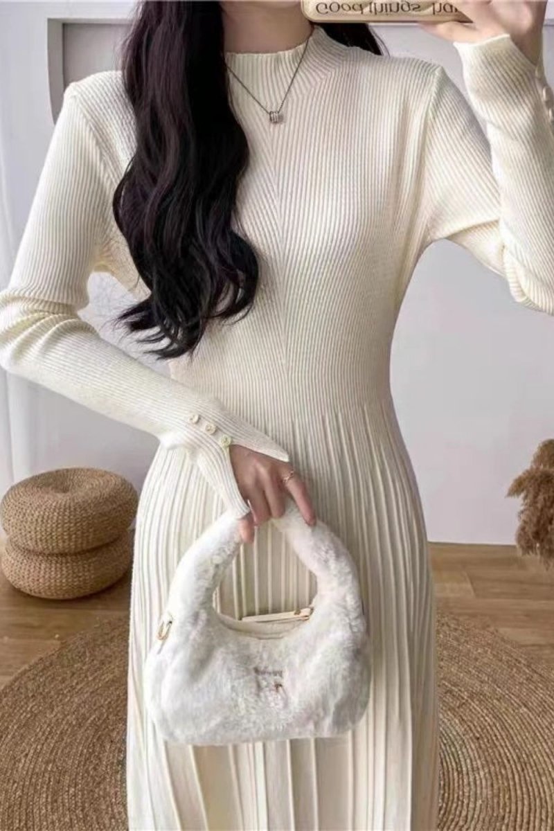 Model wearing the Kouvr Fashion long sleeve pleated knit maxi dress in cream, posing in a minimalist room