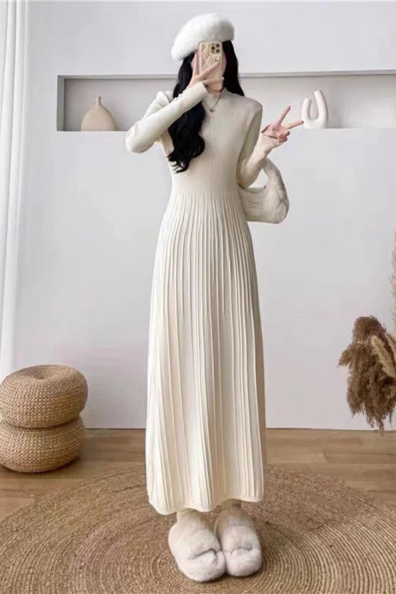 Model wearing the Kouvr Fashion long sleeve pleated knit maxi dress in cream, posing in a minimalist room