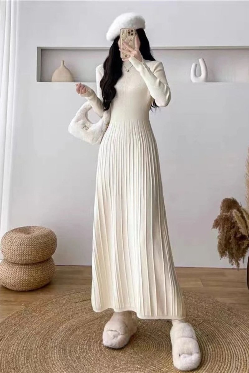 Model wearing the Kouvr Fashion long sleeve pleated knit maxi dress in cream, posing in a minimalist room