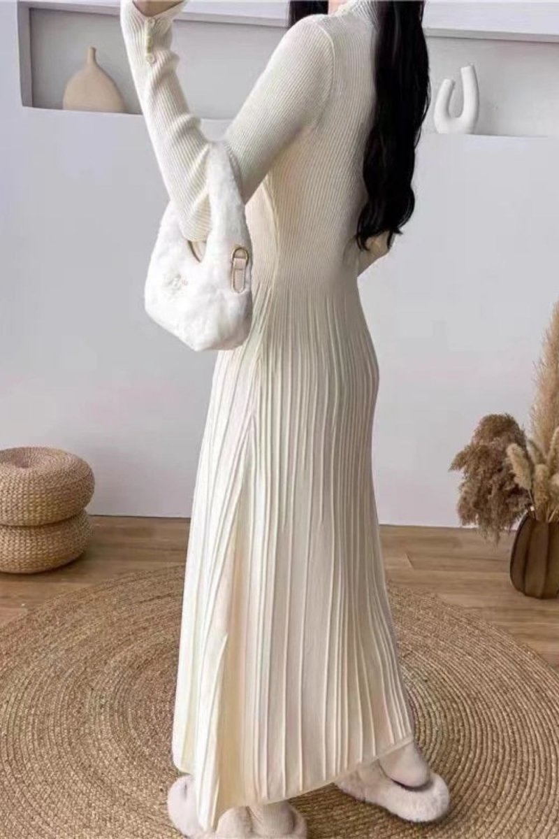 Model wearing the Kouvr Fashion long sleeve pleated knit maxi dress in cream, posing in a minimalist room