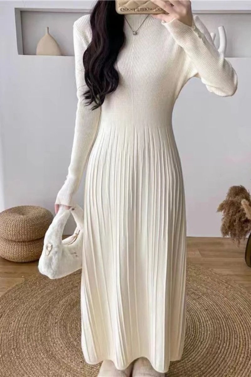 Model wearing the Kouvr Fashion long sleeve pleated knit maxi dress in cream, posing in a minimalist room