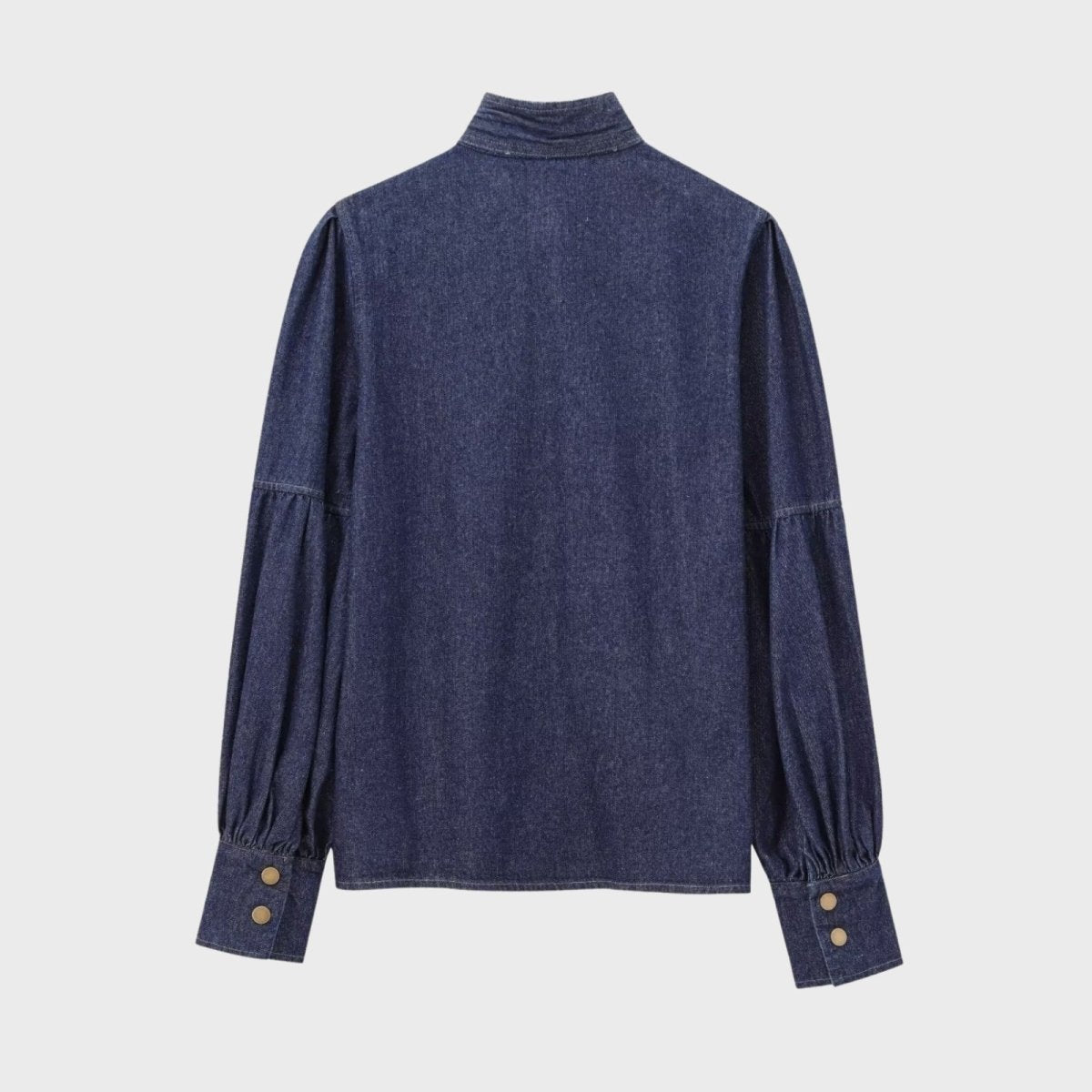 Back view flatlay of the Kouvr Fashion denim blouse, showing the details of the puff sleeves, yoke, and wide buttoned cuffs.