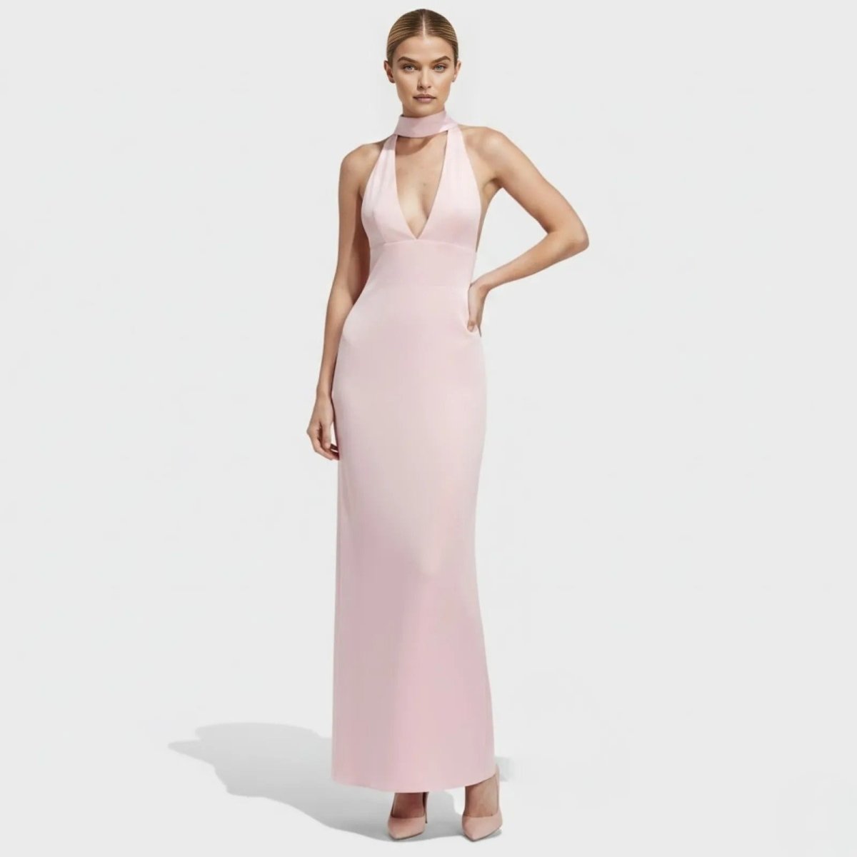 Model wearing the Sharon blush pink halter neck maxi dress from Kouvr Fashion, showing the plunging v-neckline and elegant floor-length silhouette.
