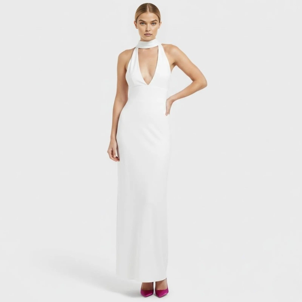 Model wearing the Kouvr Fashion Sharon white halter neck gown, showing the deep V-plunge neckline and floor-length silhouette.