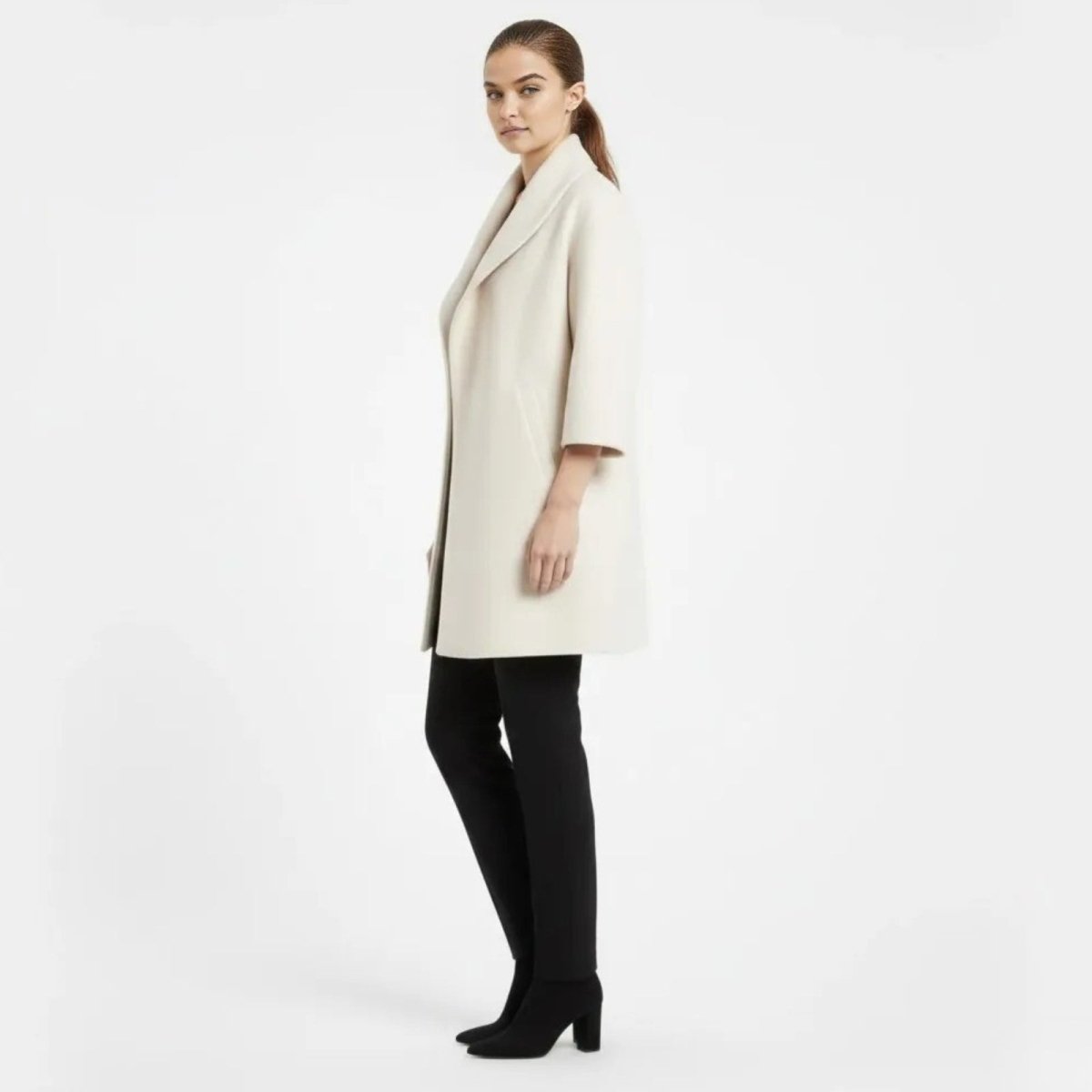 Side profile of a model wearing the Kouvr Fashion three-quarter sleeve white wool coat.
