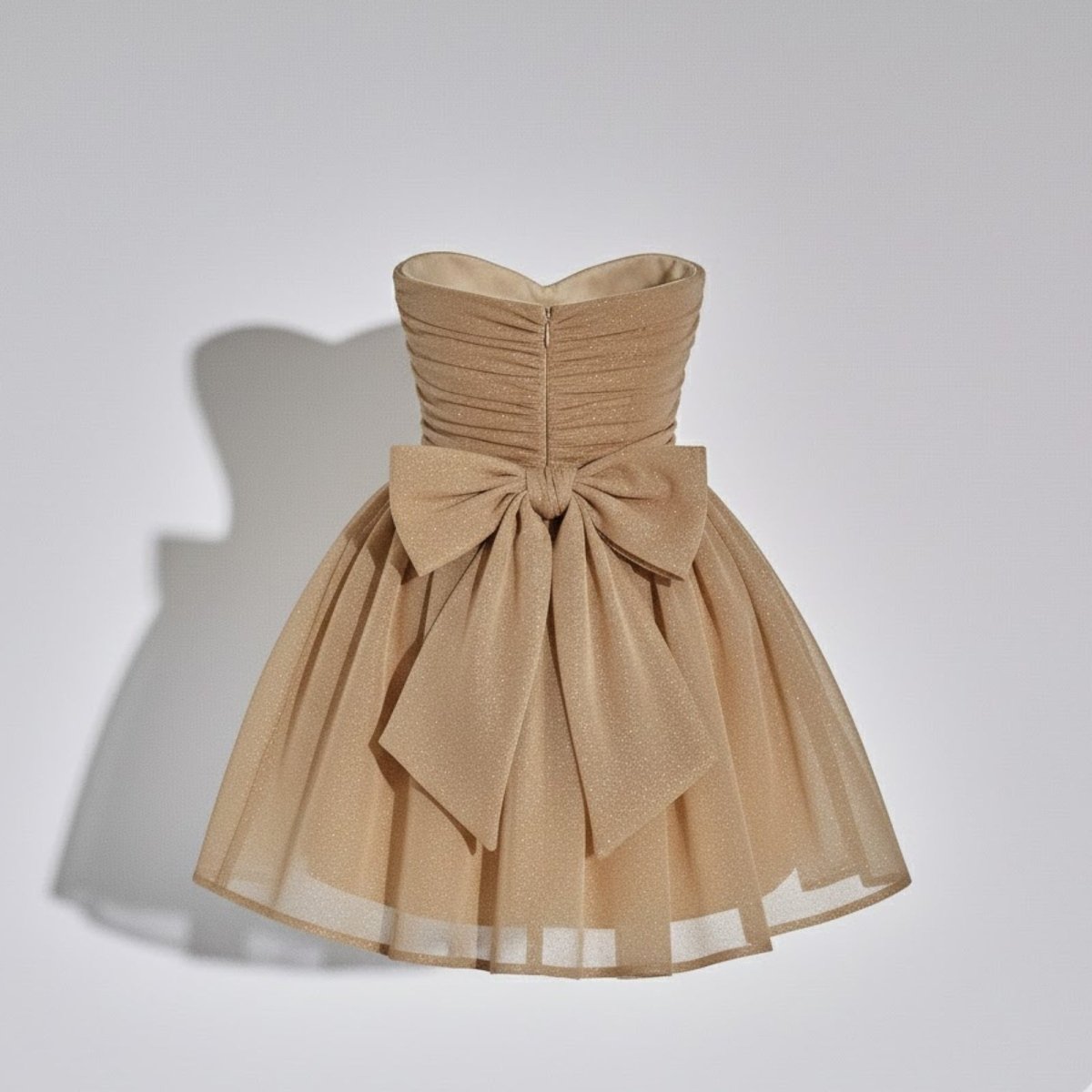 Product-only photo of the back of the Kouvr Fashion light tan mini dress, focusing on the structured oversized bow and concealed zipper.