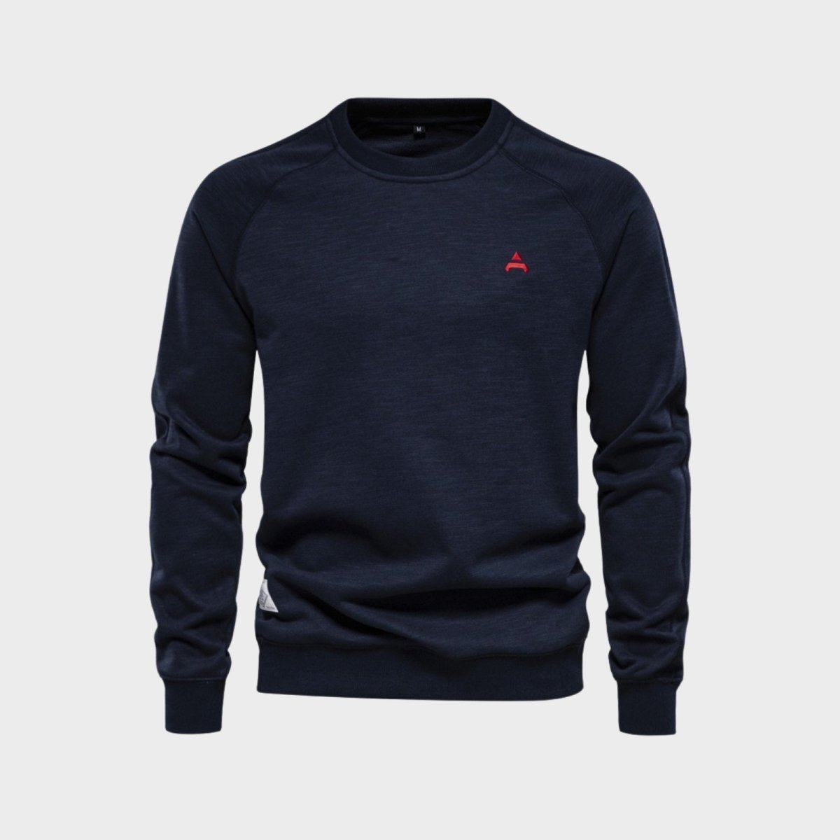 Flatlay product shot of the Kouvr Fashion Deacon crewneck sweater in navy blue, showing the red embroidered logo and fabric texture.