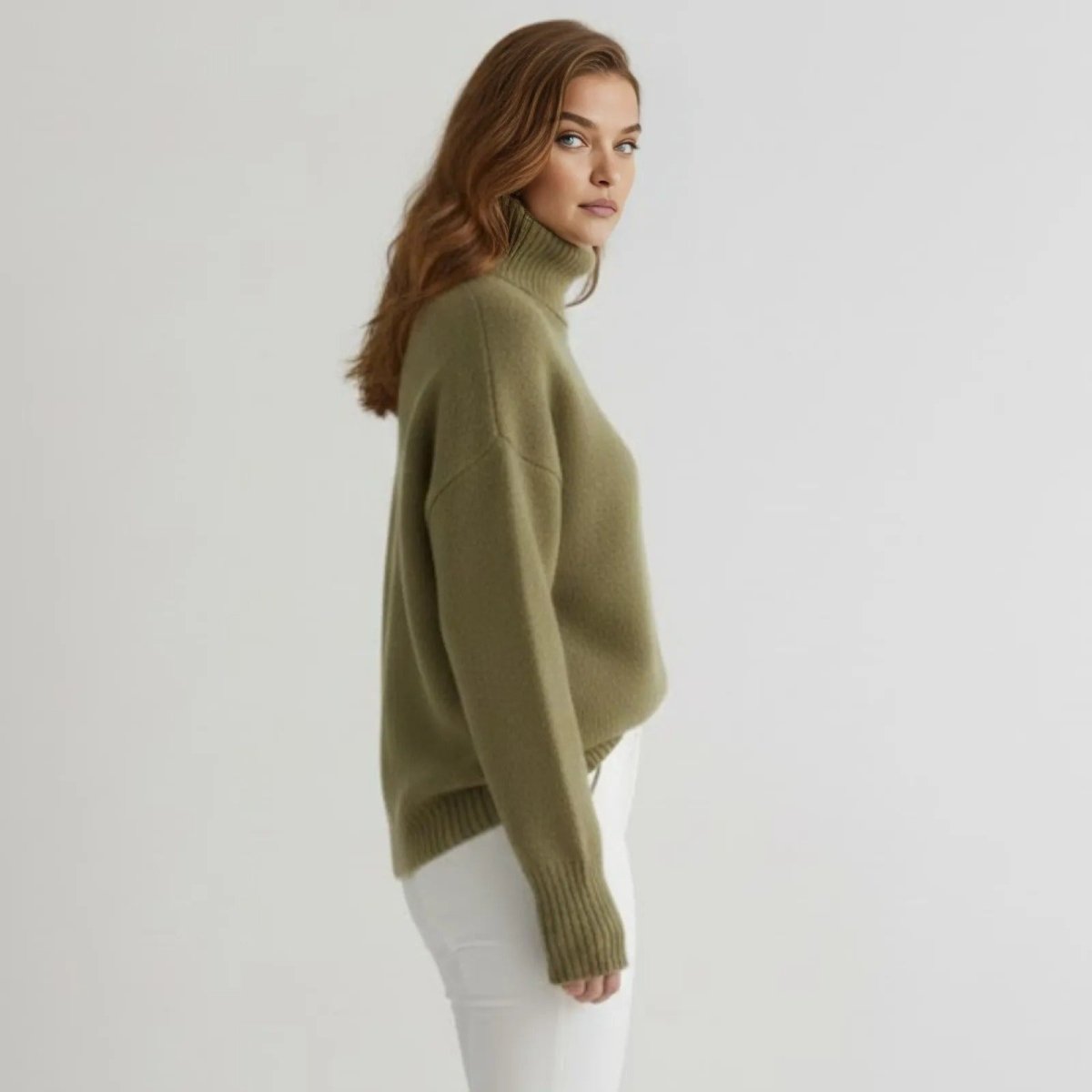 Side profile of a model in the Kouvr Fashion olive green cashmere turtleneck sweater showing its relaxed, oversized drape and fit.