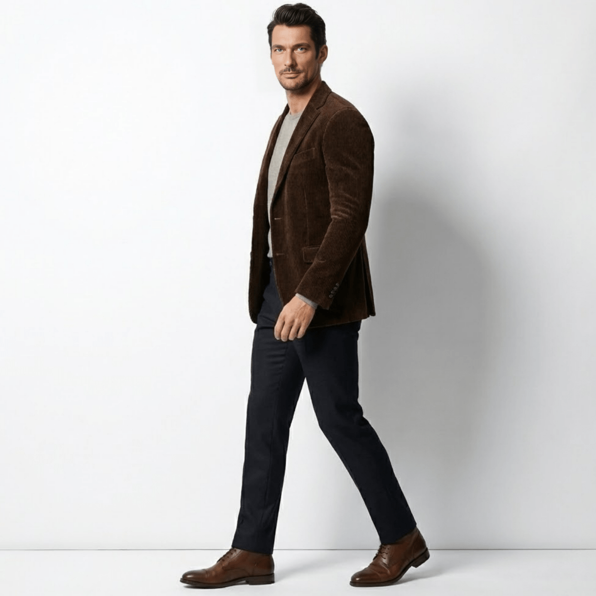 Side profile of a man walking in a tailored brown Italian cotton corduroy sport coat by Kouvr Fashion.
