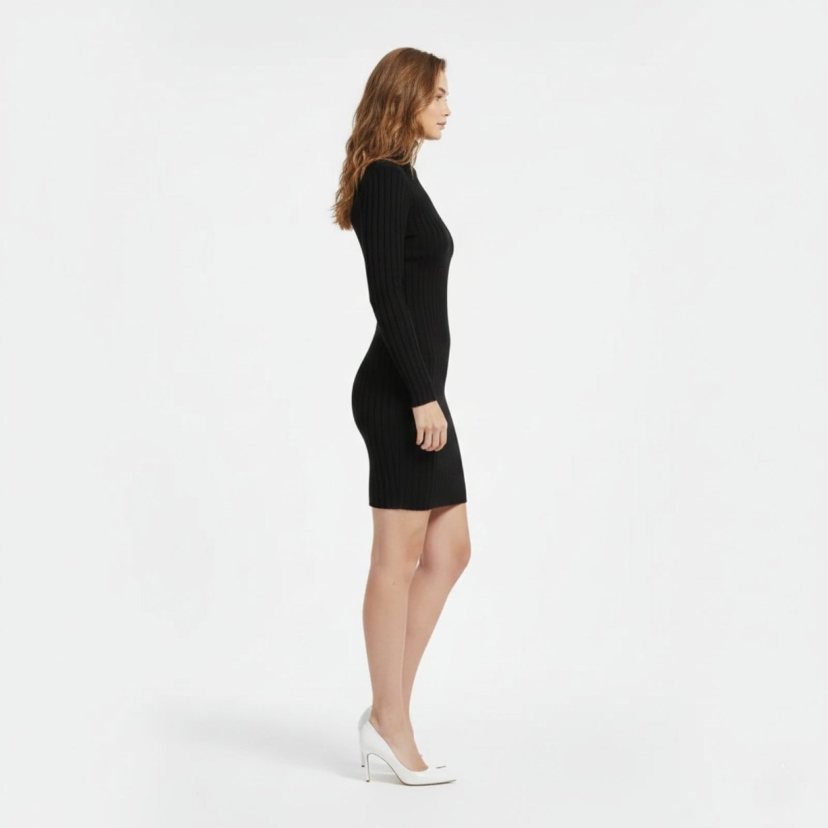Side profile view of a woman in a black ribbed turtleneck mini dress showcasing the figure-hugging fit.