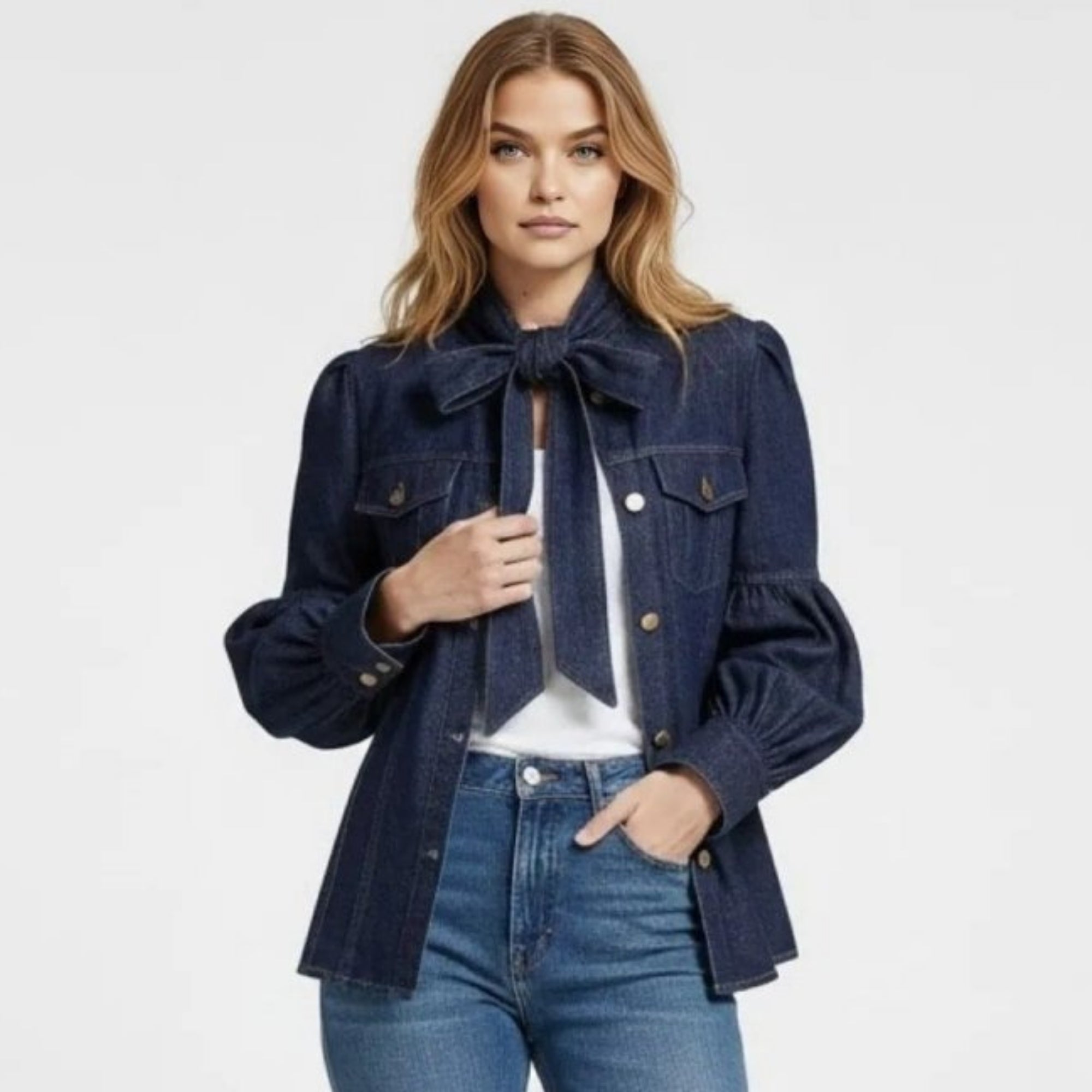 Model wearing the Kouvr Fashion dark wash denim blouse with a Alberta bow tie neck and puff sleeves, styled with straight-leg blue jeans and brown sandals.