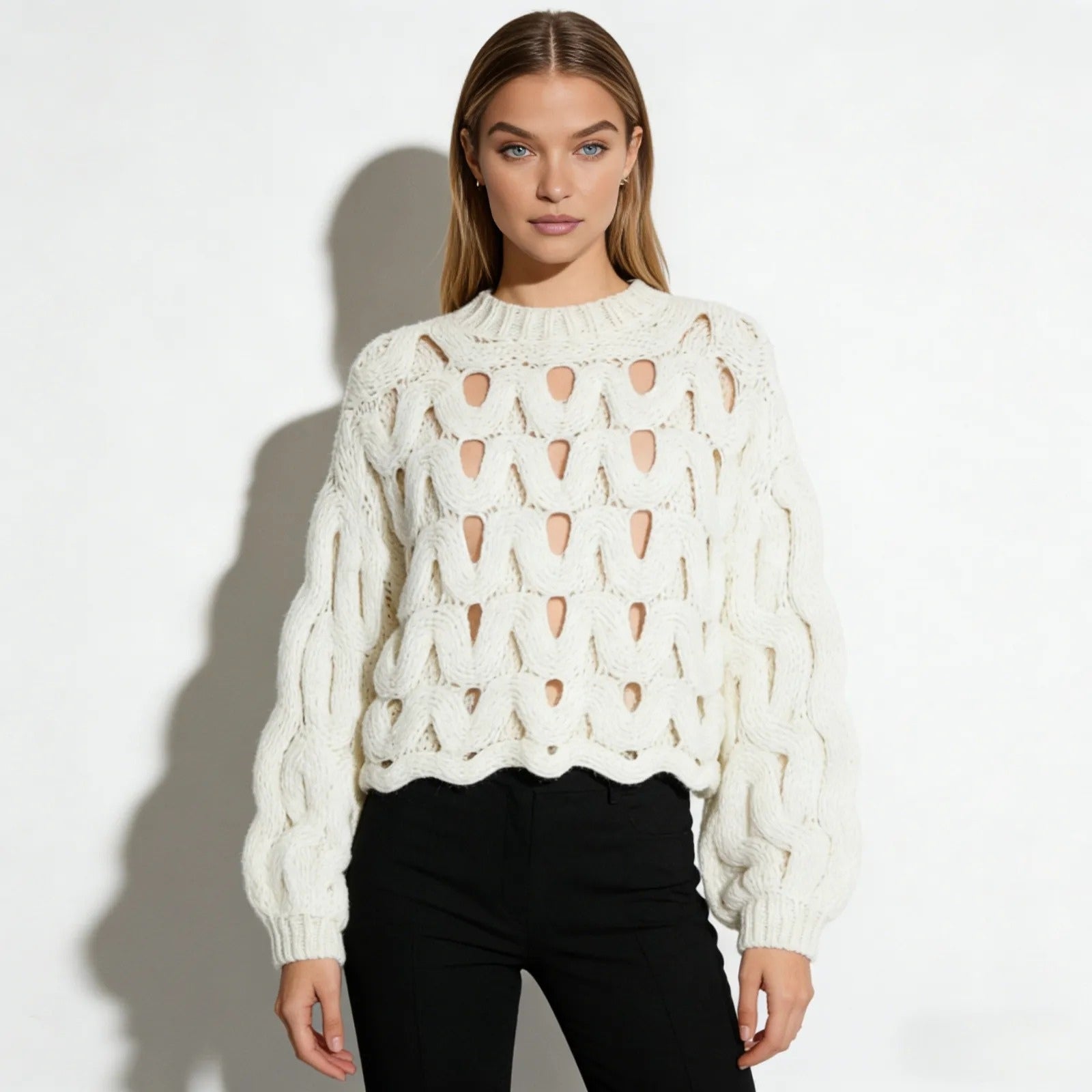Model facing forward wearing the Kouvr Fashion white cutout chunky knit sweater with black trousers against a white background.