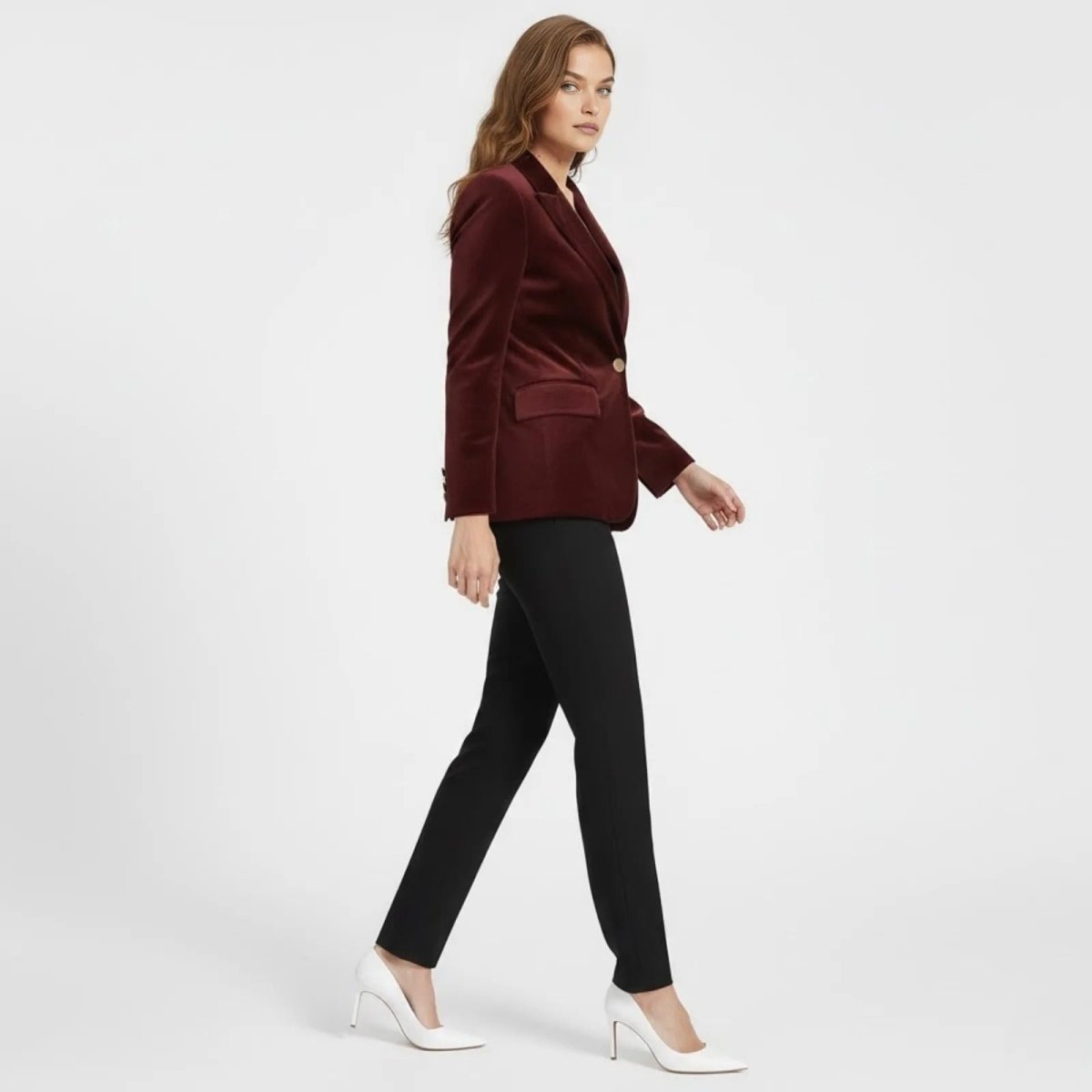 Side profile of a model walking in the Kouvr Fashion tailored burgundy velvet blazer, showcasing its fit and structure.