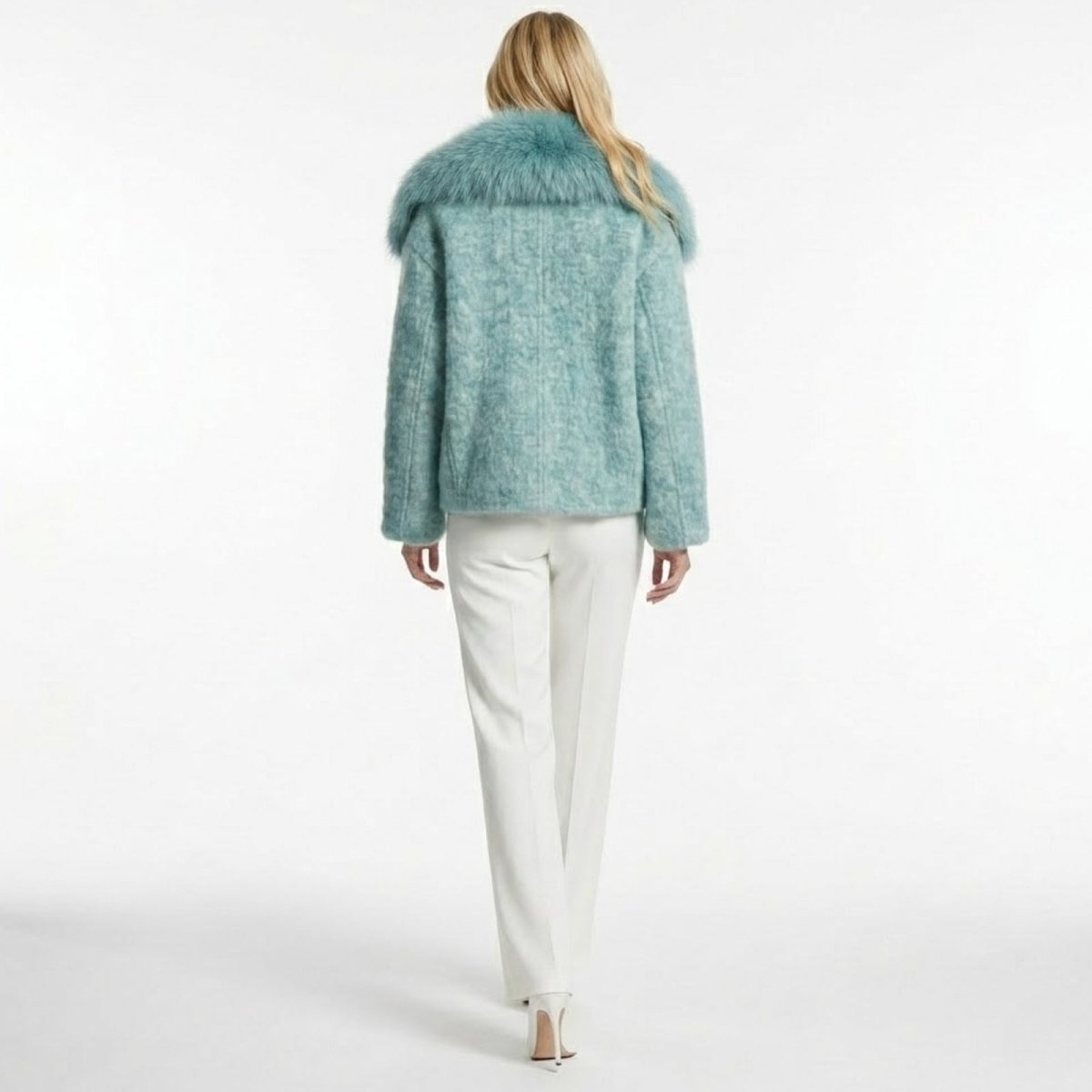 Back view of a model wearing the Kouvr Dorothy blue jacket, showcasing the fit and the full spread of the plush faux fur collar.