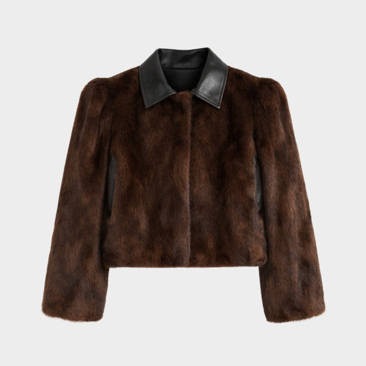 Close up of Kouvr jacket showing texture of brown faux fur, sharp black leather collar, and hidden front closure.