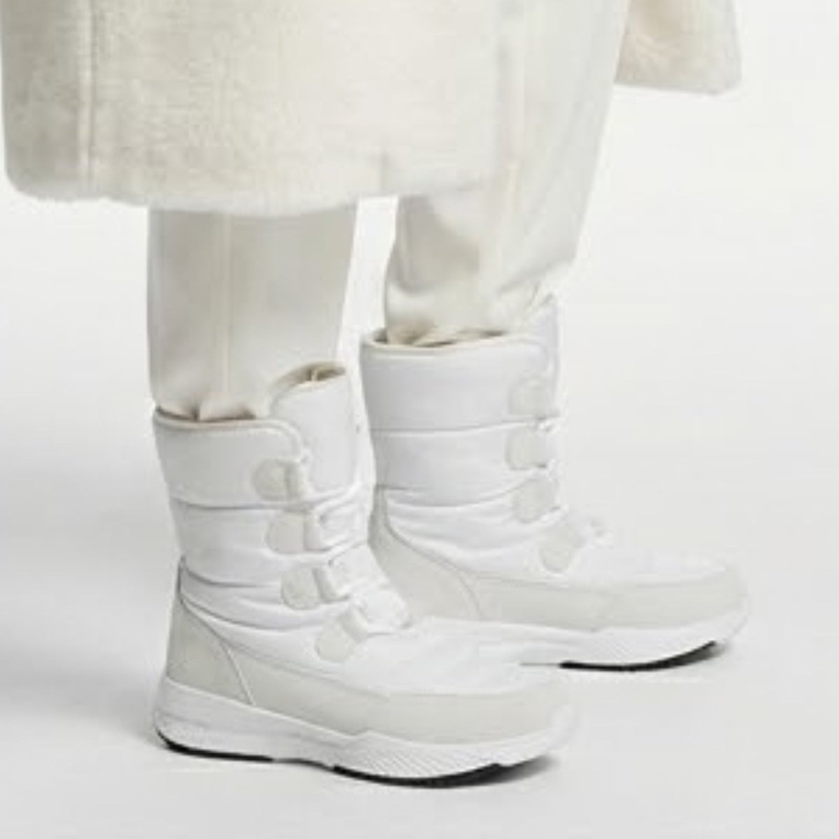 Close-up side view of the Kouvr Gianna white waterproof snow boots showing the D-ring lacing system and cushioned ankle support.
