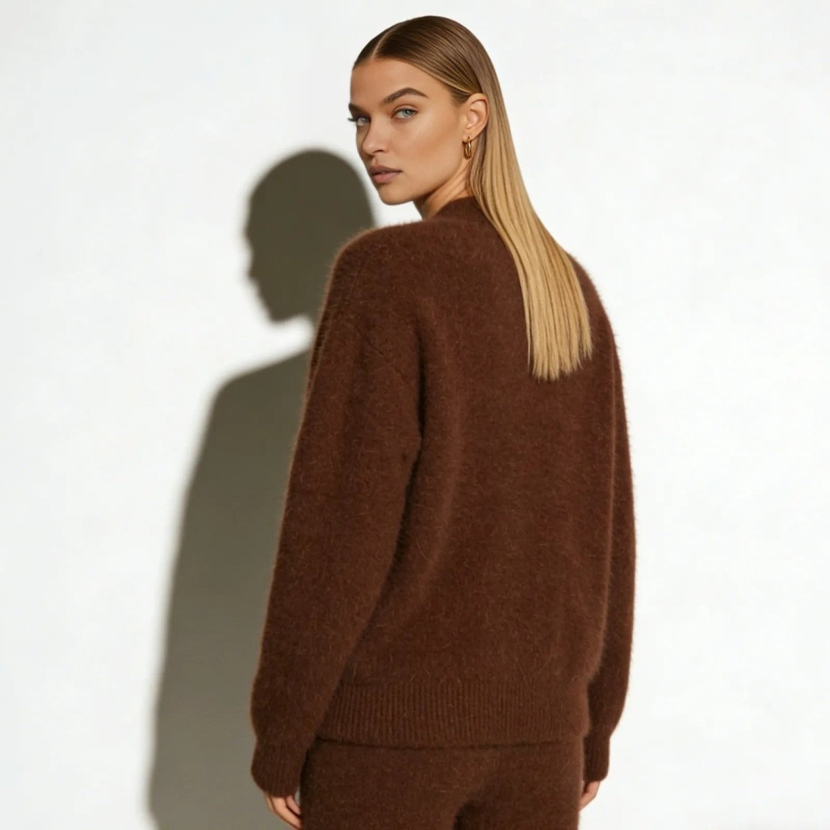 Side profile of a woman wearing a soft, fuzzy brown cardigan from Kouvr, showing its oversized, relaxed fit and sleeve length 