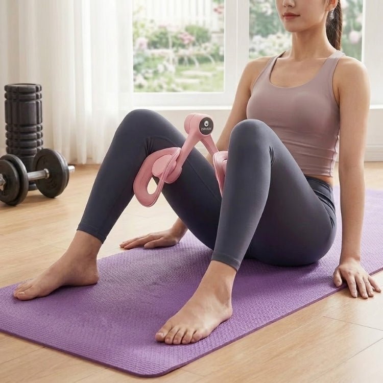A woman with dark hair in activewear sits on a purple yoga mat performing an inner thigh squeeze exercise using the pink KOUVR device during a home workout session