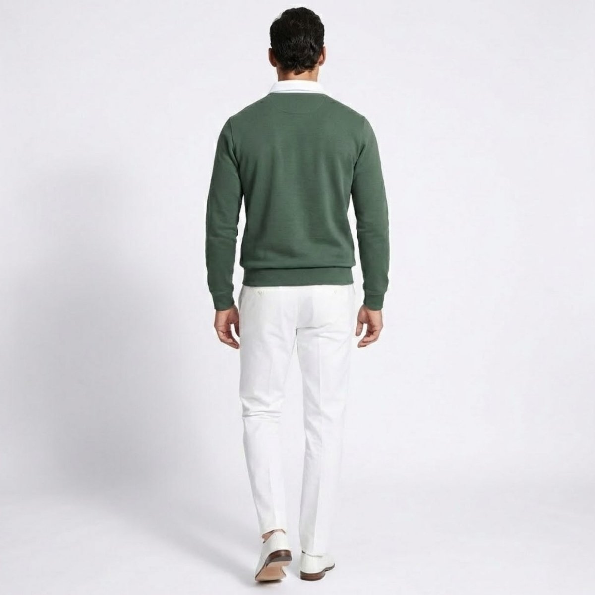 Back view of a man wearing the Kouvr  green knit polo sweater with white trousers.