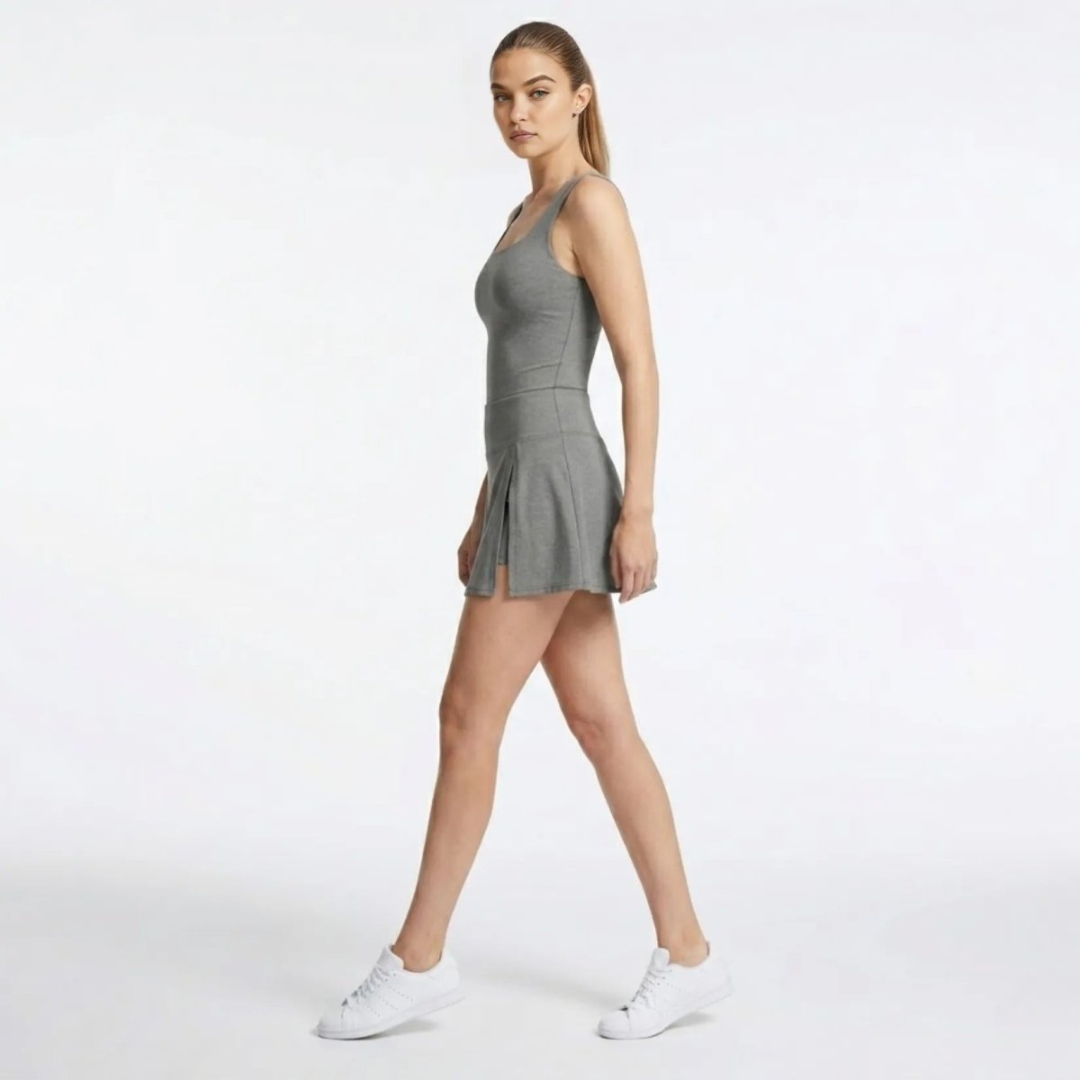 Side view of women's activewear grey mini skort showing built-in shorts and side pleat detail.