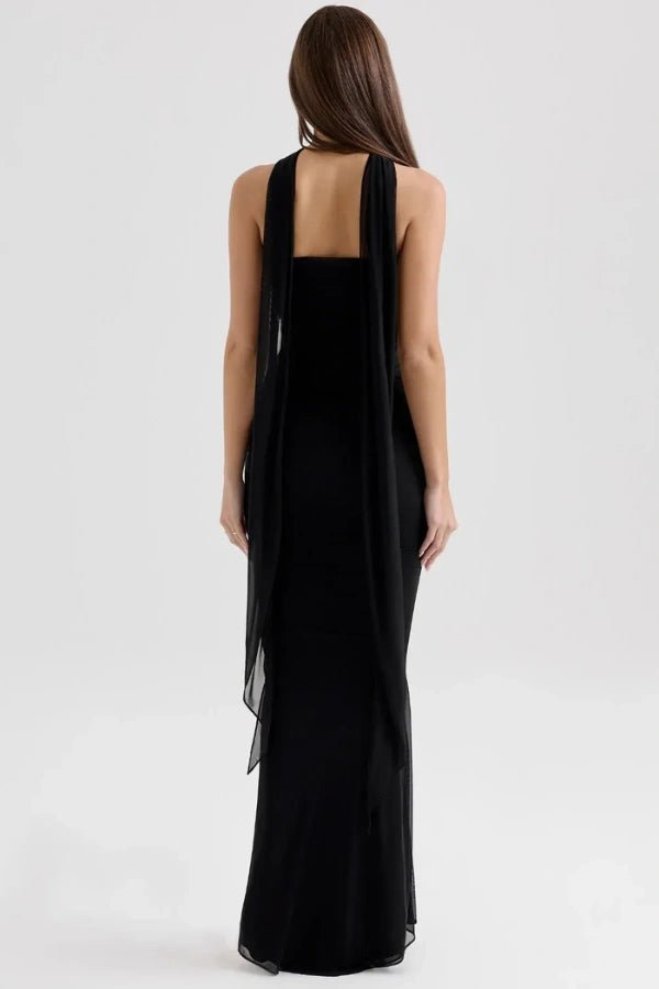 Model from behind wearing the Kouvr Hailey black evening gown, showcasing the open back and dramatic twin chiffon scarf details that flow to the floor.