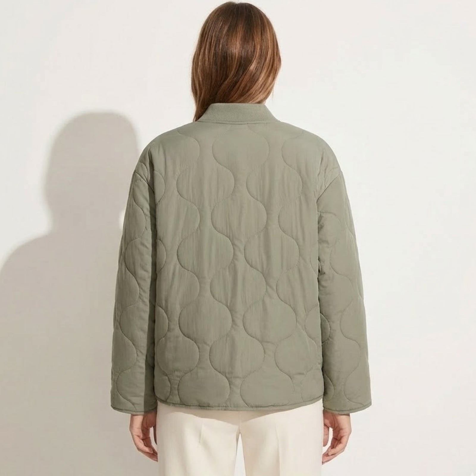 Back view of the Kouvr Harmony sage green quilted jacket on a model, showcasing the full onion quilting pattern and clean silhouette.
