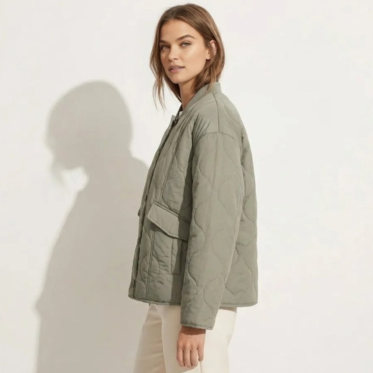 Side profile of a model in the Kouvr Harmony sage green quilted jacket, highlighting the sleeve volume and patch pocket detail.