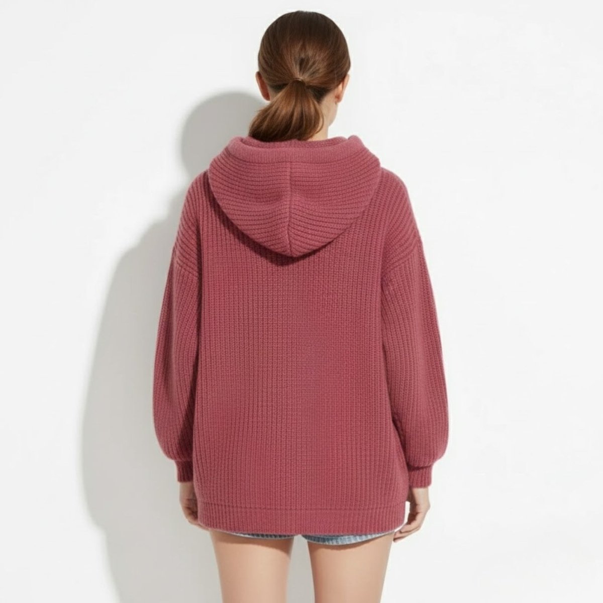 Back view of a model wearing the Kouvr Haven chunky knit hoodie in dark pink, showcasing the hood and longline tunic length.