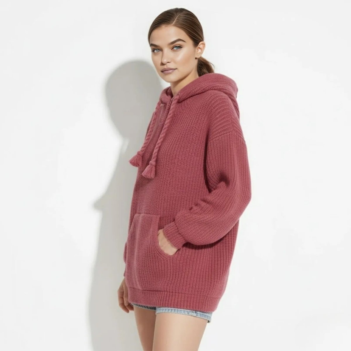Side profile of a model in the Kouvr Haven chunky knit hoodie in dark pink, showing the oversized fit and balloon sleeve detail.